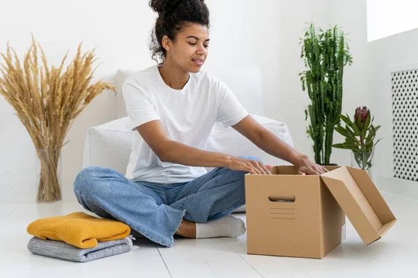 Attractive African American Teenage Girl Putting Apparel Box Modern Room — Stock Photo, Image
