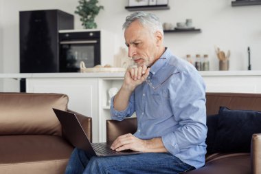 Çevrimiçi çalışan serbest çalışan emeklilerin profil görüntüsü, ev ofisinden dizüstü bilgisayardan video görüşmesi yapmak. Sakin ol kıdemli adam kablosuz teknolojiyi kullanıyor, haberleri kontrol ediyor, film izliyor.