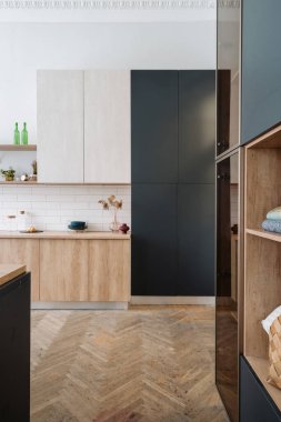 Yenilenmiş bir daire ve konforlu bir yaşam. Mutfaktaki yeni mobilyaların dikey görüntüsü ahşap dolap, depo dolabı ve oda parke zemin.
