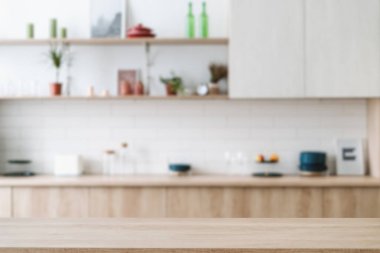 Arka plandaki soyut bulanık iç görünüme karşı boş ahşap tezgah üzerine seçici bir odaklanma. Ürün gösterimi kavramı. Ahşap mobilyaları, dolabı ve yemek masasında boş yeri olan lüks bir mutfak.