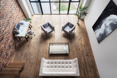 High above view of room in loft style with modern furniture and decor. Contemporary office interior design. Luxury apartment. Cozy workplace in multilevel building