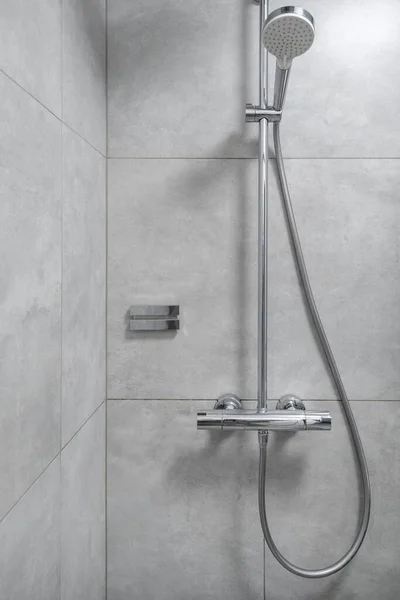 Stainless shower zone with rain head in grey bathroom. Shower faucet usage. Modern hotel bathroom facilities. Luxury apartment after renovation for sale. Personal hygiene