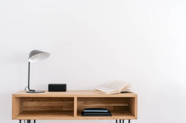 Lamba, kitap ve müzik sütunu beyaz duvarın yanındaki ahşap masada. Modern oda iç tasarımı. Merkez ofis konsepti. Ev rahatlığı. Rahat bir iş yeri