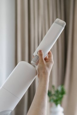 Kadın, el bilgisayarı ve kablosuz elektrik süpürgesinin küçük fırçasını değiştirir. Temizlik hizmeti konsepti. Ev aletlerinin parçaları denetleniyor ve değiştiriliyor