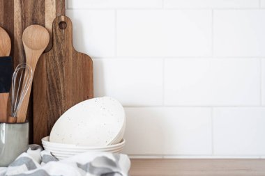 Ahşap rafta alet edevat ve mutfak gereçleri koleksiyonu. Spatula, kaşık, fincanda çırpma, kesme tahtalarına yakın, seramik kaseler, tezgahta havlu. Çanak çömlek ve mutfak malzemeleri, kopyalama alanı