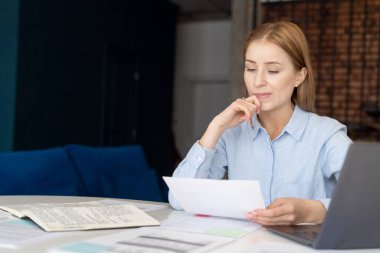 Portrait of thinking businesswoman carefully reading documents. Problems solving. Home office. Examining utility bills paper. Displeased financial report