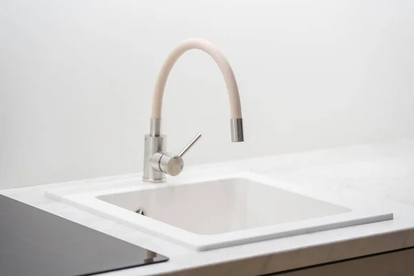 Closeup of beige sink into Scandinavian kitchen interior design in white tones. Home comfort. Modern kitchen equipment and details. House after renovation