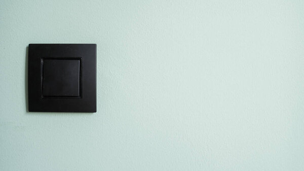 Banner and close up shot of electric light switch in black plastic frame on green copy space wall. Electricity conservation, concept of resource consumption, power elements in apartment