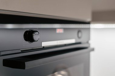 Selective focus on control panel with setting button on new built-in electric oven. Metal handle on empty microwave with defrosting and grilling mode, close up. Household appliance in modern kitchen