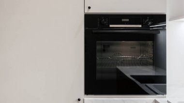 Front view of built-in electric oven on modern white kitchen. New household appliance in modern apartment. Professional baking equipment at contemporary home. Advertising concepts