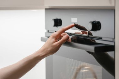 Modern elektrikli fırının dokunmatik ekranındaki kadın düğmesine bas. Ev hanımı farklı pişirme modunda mikrodalga fırında kontrol paneli kullanıyor. Ev malzemelerinde kadın kontrol sıcaklığı