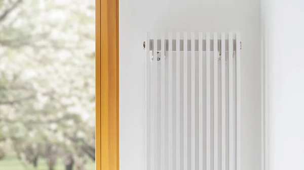 Cropped view of white stylish radiator in contemporary living room interior design. Central heating installation. Warm home. Room heater with temperature controller