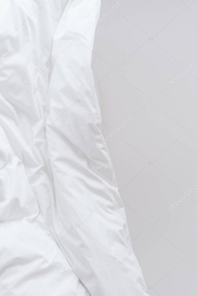 Crumpled blanket for comfort and healthy sleeping in bedroom. Removal of stains from bed linen. Laundry service and dry cleaning for white bedsheet. Advertising concept of duvet, copy space background