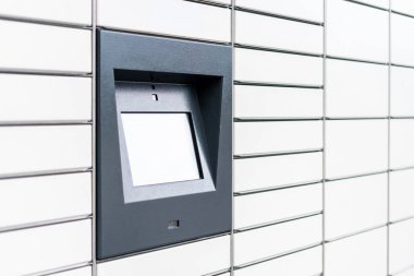 Kendi servisli beyaz otomatik posta terminalinin yan görüntüsü. Kapıları kilitli posta hücreleri. Şehir posta kutularının yakınındaki ekran görüntüsüne dokun. Ekspres teslimat ve kargo konsepti