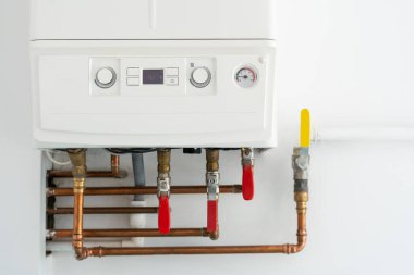 autonomous heating boiler with control panel, buttons, display with temperature indicator and valves on pipes at home kitchen