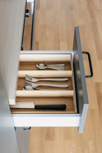 opened drawer with organized box from wood for silverware or section for forks, spoons, teaspoons and knife at contemporary kitchen