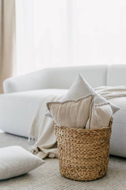 Cropped view of pillows in basket in stylish living room interior design. House after renovation. Relax concept. Home comfort. New flat details