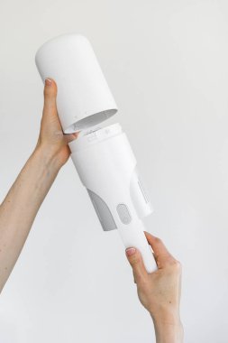 Replacement of the air filter on the portable and cordless vacuum cleaner. Process of changing battery on a electric hoover. Maintenance checking household appliance against white copy space wall