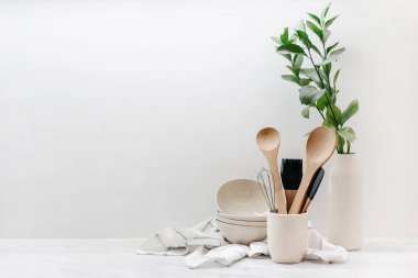 Closeup of eco-friendly kitchenware, utensils, towel and plant on table in kitchen with white walls. Home comfort. Household equipment. Earth-friendly products