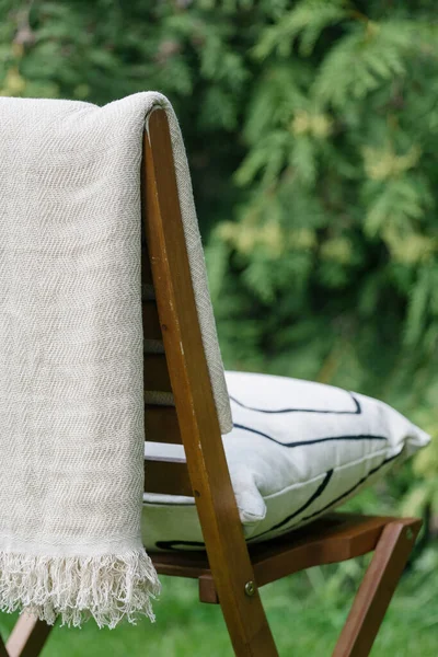 garden furniture or wood lounge seat with cushion and white blanket in backyard on blurred green background