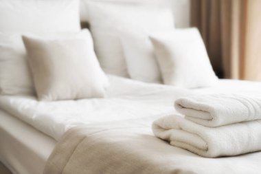 Otel yatağında beyaz temiz havlulara odaklan. Oda servisi konsepti. Yeni yatak takımları ve kişisel hijyen malzemeleriyle kapatılıyor. Konaklama, konukseverlik ve motel işleri. Yatak odasının içi.