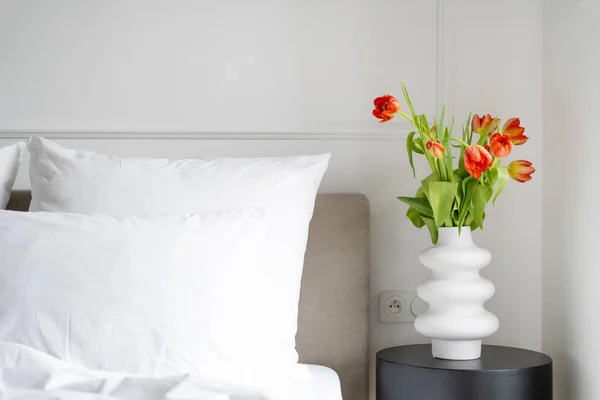 Fresh flowers on bedside table, cozy morning, home decor, contemporary bedroom interior design in Scandinavian style after renovation, hotel room details
