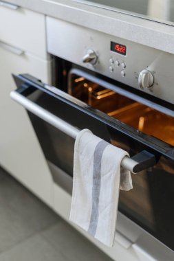 İçinde açık kapı ve ışık olan dahili elektrikli fırının kapatılması, zamanlayıcı, düğme düğmesi ve düğmesi olan kontrol paneli, çağdaş mutfakta havluyla tutacağı olan
