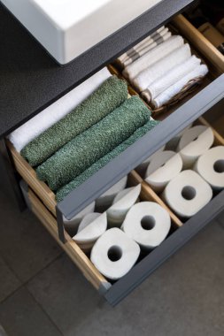Tahta kabın içinde temiz banyo havluları ve hasır sepetin içinde Terry yüz havluları olan açık çekmece.