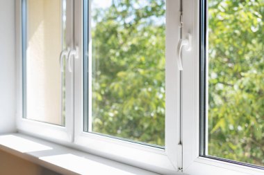 Modern eve monte edilmiş beyaz metal çerçeveli yeni plastik pvc pencere, bulanık yeşil ağaçlar. reklam kavramları