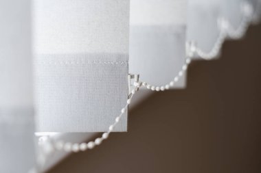 Modern apartmandaki kumaş grisi jaluzilerin ya da dikey jaluzilerin detaylarına yakın çekim. Tekstil hoparlörlü oturma odası