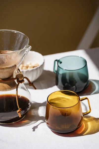 alternative method of brewing coffee and two glass cups with espresso on table with linen tablecloth at apartment kitchen