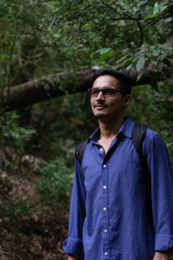 Gözlüklü genç Hintli adam ormanda gözlerini kaçırıyor. Kurtulan düşünürken devrilmiş bir ağacın yanında