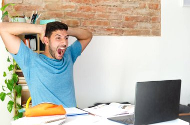 stressed and panicked man in front of the computer. student screaming at not finding his job. businessman panicking at the numbers of his small business. young man receives bad news.