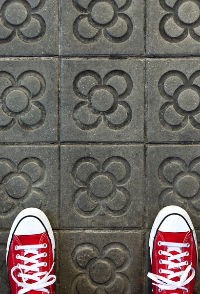 unrecognizable person standing on the tiles of barcelona with red sneakers. famous sidewalk of barcelona ideal for wallpaper, postcard or background. aerial view