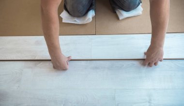 Beyaz kaplamalı erkek elleri. Yeni lamine ahşap zemin döşeyen adam