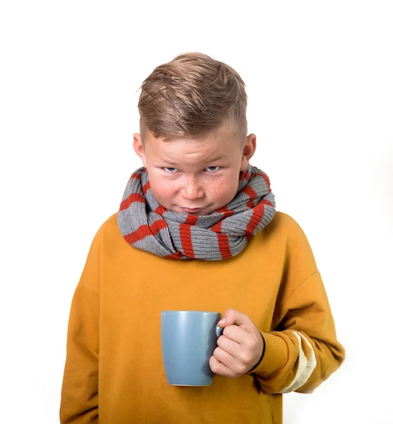 Ребенок болен с чашкой горячего чая или молока в руках изолированы на белом фоне. Парень с гриппом пьет воду. Ученик не хочет идти в школу. — стоковое фото