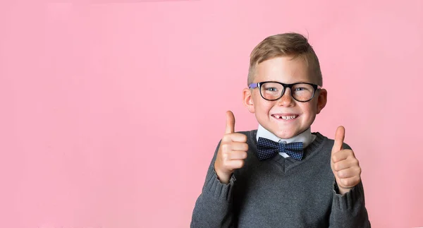 Portrait of confident school child showing thumbs up isolated one pink backgroud. Kid in glasses with happy face — Stock Photo, Image