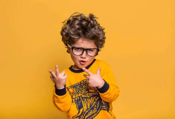 Cool fashion child in glasses isolated on yellow background. Happy boy model. Stylish confident little kid. Kindergarten five year old handsome boy. Boy pointed up with finger — Stock Photo, Image