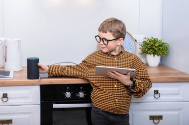 Ses kontrollü akıllı hoparlör. Tabletli okul çocuğu Amazon Alexa Echo Dot ile konuşuyor. Çocuklar için eğitim programı. Çocuk Alexa 'yla konuşuyor, ona emir veriyor ve neyi açması gerektiğini söylüyor.