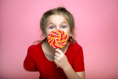 Lolipopu olan küçük bir çocuk. Renkli şekerli kırmızılı kız. Okulun yeniyetme çocuğu çubukta lolipop yiyor. Karamel dükkanı. Tatlı çocukluk hayatı. Diş bakımı konsepti. Tatlı düşkünü. Lezzetli
