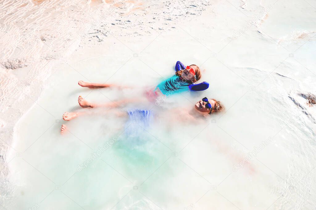 Kids boy and girl relaxing in hot white spring water jet. Thermal bathes in Turkey. Hatural hot spring spa baths outdoors. Child in sunglasses in summer vacation