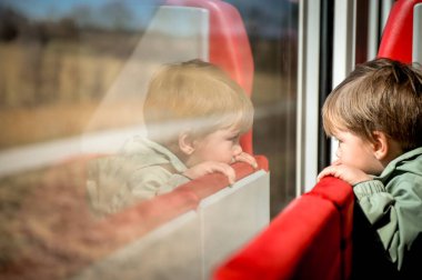 Bebek pencereden bakıyor. Hızlı trendeki çocuk. Tatilde demiryolu ile seyahat et. Tren vagonundaki çocuklar. Tren vagonundaki çocuklar. Genç yolcular için eğlence