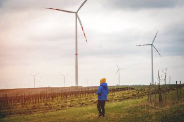 Çocuğun geleceği, alternatif enerjidir. Rüzgâr çiftliğindeki çocuk. Doğada gezen mutlu çocuk. Yenilenebilir enerji ve sürdürülebilir kaynak rüzgar değirmenleri. Rüzgar türbini. Sürdürülebilir iklim görselleri