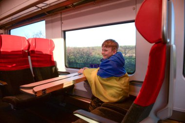 Çocuk Ukrayna bayrağıyla kaplanmış trende oturmuş pencereye bakıyor. Savaşta devlet desteği. Birleşik Avrupa Rusya 'ya karşı. Dünya için umut. Endişe ve beklenti. Ukrayna 'yı Kaydet