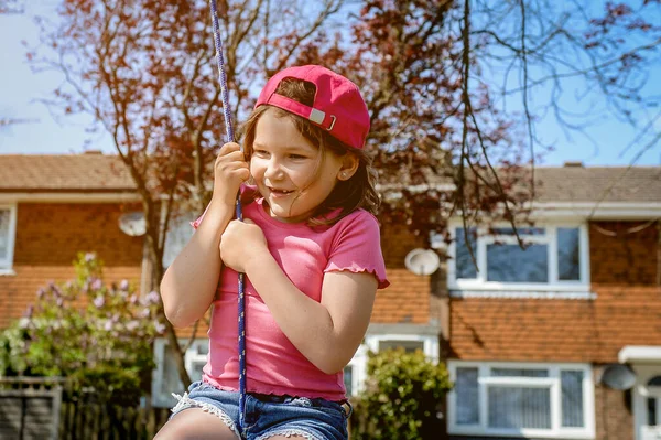 Çocuk dışarıda oyun oynuyor ve salıncak sallıyor. Çocuklar okulda ya da anaokulunda oynarlar. Renkli salıncakta hareketli bir çocuk. Yağmurlu havada çocuklar için sağlıklı yaz etkinliği. Küçük çocuk sallanıyor.
