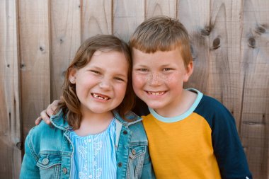 Funny portrait of boy and girl smiling with gaps in teeth. Children have fun showing milk theath. Close up of pre-teen friends in a park. Freckled boy face with his sister on summer vacation.