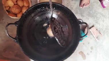 Hintli bir kadın kutsal adaklar sunuyor. Pirinç unu ve tırmığı karıştırıp yağda kızartarak yapılıyor. Hindistan 'da geleneksel tatlı yapan bir kadın. Hintli bir kadın yağda kızarıyor..