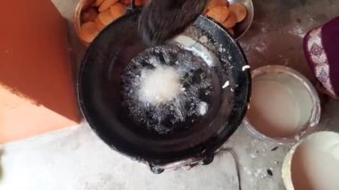 Hintli bir kadın kutsal adaklar sunuyor. Pirinç unu ve tırmığı karıştırıp yağda kızartarak yapılıyor. Hindistan 'da geleneksel tatlı yapan bir kadın. Hintli bir kadın yağda kızarıyor..