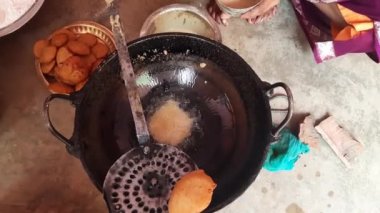 Hintli bir kadın kutsal adaklar sunuyor. Pirinç unu ve tırmığı karıştırıp yağda kızartarak yapılıyor. Hindistan 'da geleneksel tatlı yapan bir kadın. Hintli bir kadın yağda kızarıyor..