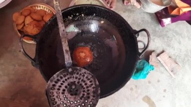 Hintli bir kadın kutsal adaklar sunuyor. Pirinç unu ve tırmığı karıştırıp yağda kızartarak yapılıyor. Hindistan 'da geleneksel tatlı yapan bir kadın. Hintli bir kadın yağda kızarıyor..